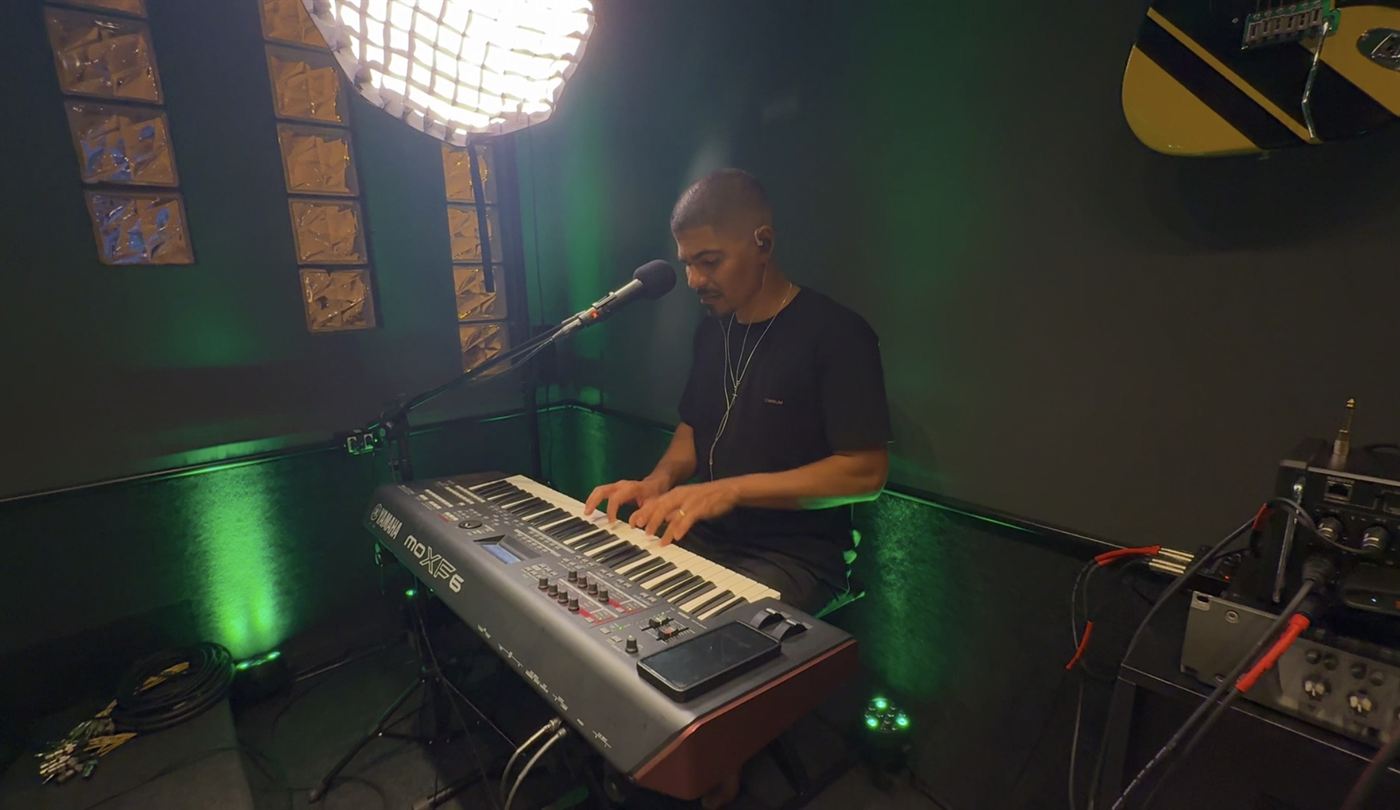 Tecladista tocando e cantando no estúdio