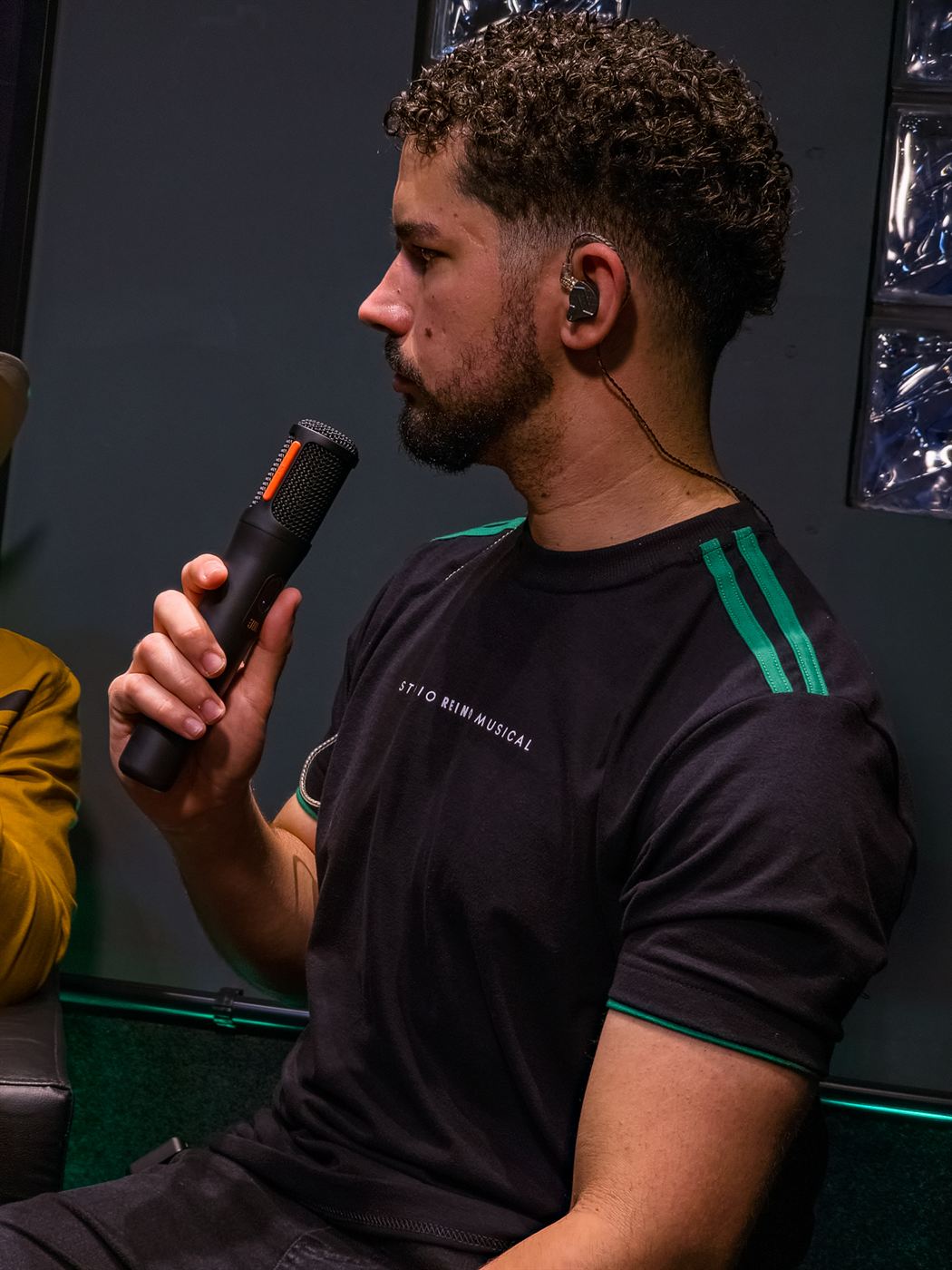 Músico falando ao microfone com camiseta do estúdio